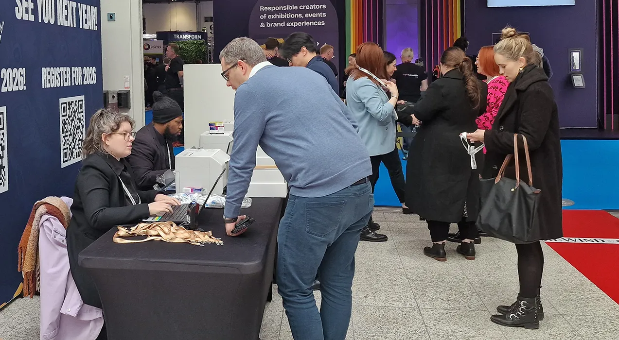 People registering and collecting badges from registration desk at entrance to exhibition hall