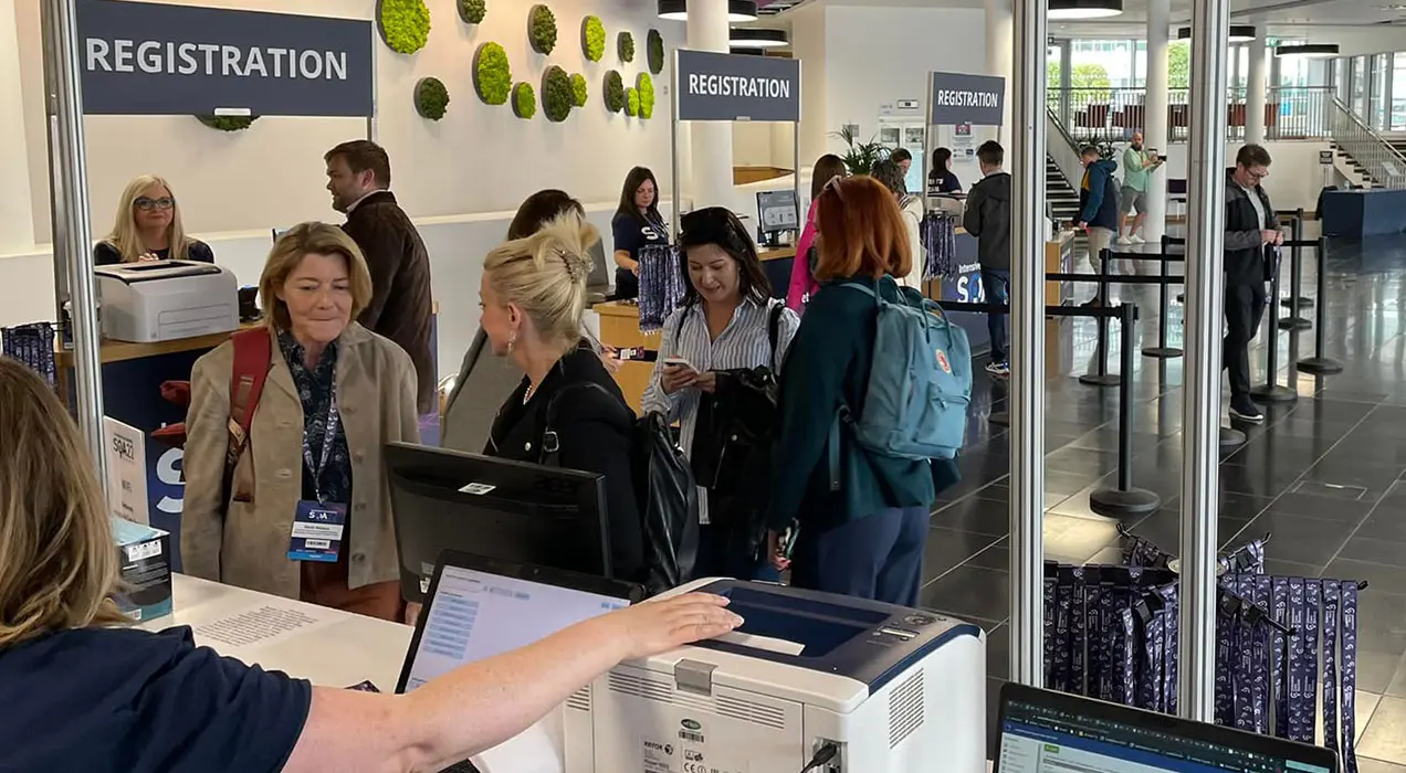 People using registration desks in entrance foyer at an event